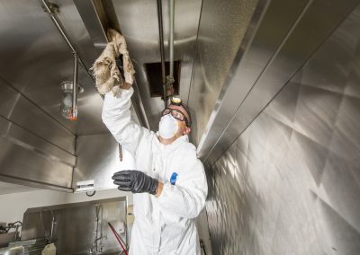 Commercial kitchen worker washing up at sink in professional kitchen