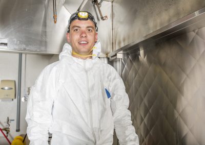 Commercial kitchen worker washing up at sink in professional kitchen