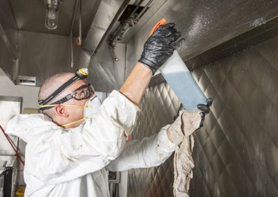 Commercial kitchen worker washing up at sink in professional kitchen